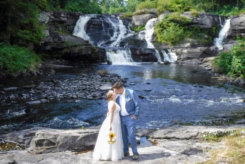 Bride and groom share a kiss in front of Resica Falls